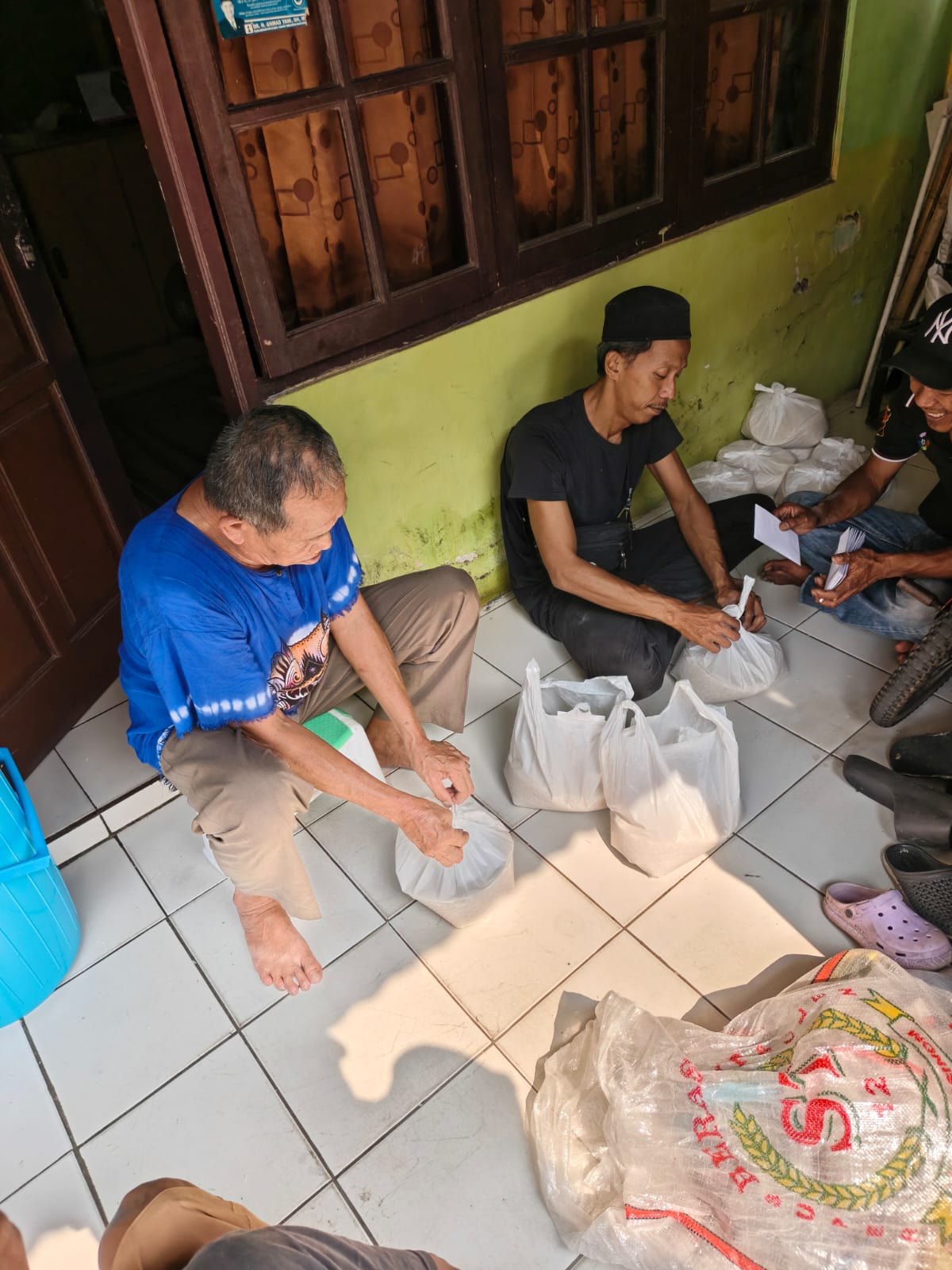 Warga bergotong royong menakar dan mengemas beras zakat ke dalam kantong plastik